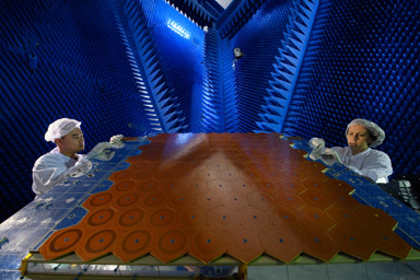 Thales Alenia Space, Toulouse (Haute-Garonne - France) 2016  <br><br>
On teste les performances d’une antenne de satellite – la structure en nid d’abeille posée sur la table – dans une chambre anéchoïque ou chambre sourde. Les cônes en mousse bleue absorbent les ondes sonores, ce qui permet de recréer le silence spatial. Des capteurs permettent entre autres de mesurer les perturbations électromagnétiques. <br><br>*****<br><br> To ensure that a telecommunications satellite carries out its mission perfectly, the performance of its antennae is tested in an anechoic chamber, aka a “sound chamber“. Lined with foam cones that absorb electromagnetic waves so as not to interfere with transmission and reception measurements, the antennae of a geostationary satellite transmit as if it were actually in space, i.e. 36 000 km from the Earth!